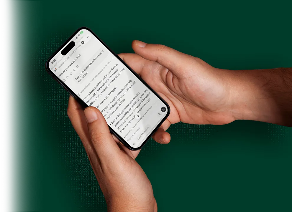 Hands holding a phone, discussing defence stocks with Claude